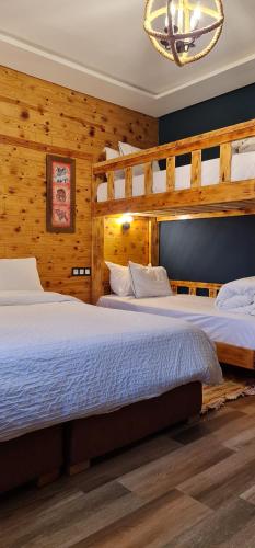 two beds in a room with wooden walls at Maurice Bonjean in Ifrane