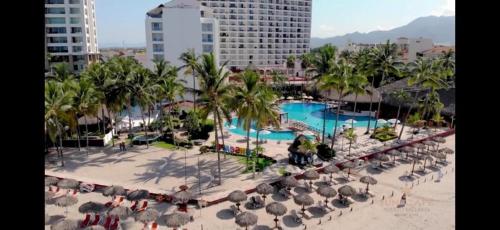 a view of a resort with a pool and chairs and palm trees at Puerto Vallarta Condo Frente al mar in Puerto Vallarta