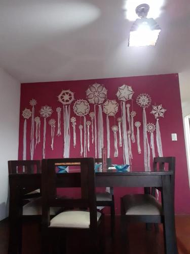 una mesa de comedor y sillas con una pared rosa en Los mandalas en San Salvador de Jujuy