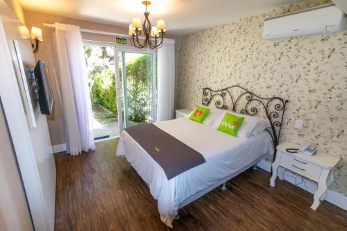 1 dormitorio con 1 cama con lámpara de araña y ventana en Pousada Floratta Recanto da Ladeira en Gramado