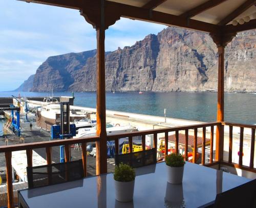 Elle comprend un balcon offrant une vue sur l'eau et la montagne. dans l'établissement Acogedor apartamento en Los Acantilados, à Acantilado de los Gigantes