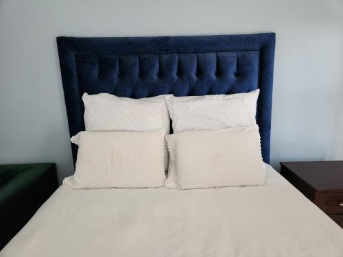 a bed with a blue headboard and white pillows at Bryanston Drive Elegant Guesthouse & Boardroom Facilities in Johannesburg