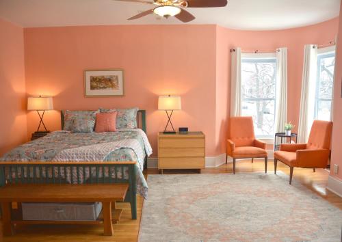 a bedroom with orange walls and a bed and two chairs at Art and Lodging in South Bend