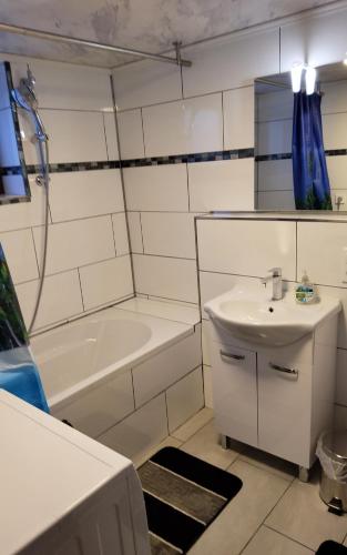 a white bathroom with a sink and a bath tub at Brodovskiy- Apartment in Neckarsulm