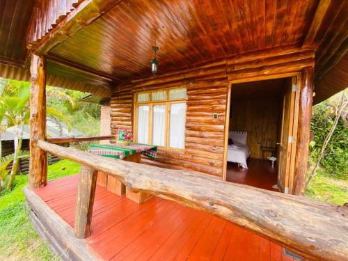 a log cabin with a wooden deck with a bedroom at Cabañas Palma Sky Lodge in Oxapampa
