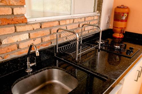 a kitchen sink with a dish drying rack on a brick wall at Chalé charmoso e aconchegante, pertinho da cidade. in Brasilia