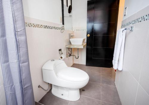 a bathroom with a white toilet and a sink at Hotel Kuska Home in Cusco
