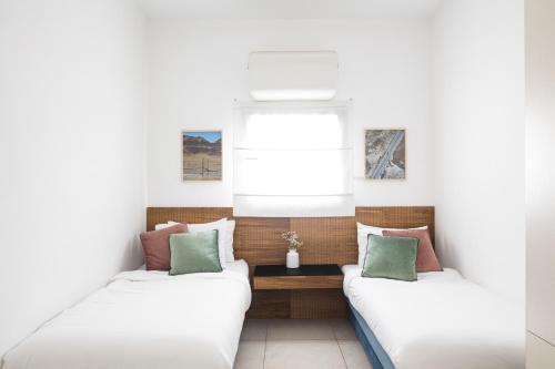 two beds in a room with a window at Mate TLV PORT - By HOMY in Tel Aviv