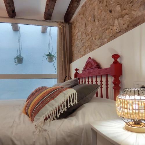 a bed with a red headboard next to a window at Cal Passió in Vimbodí
