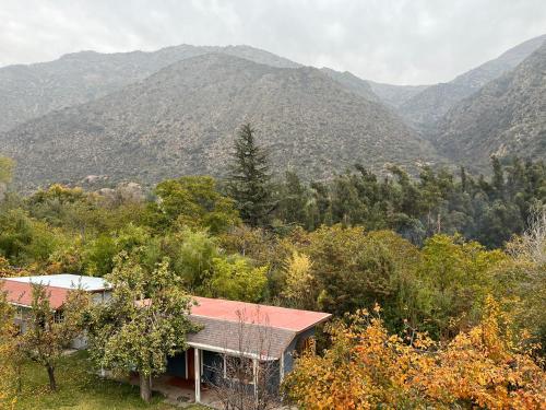une maison dans les bois avec des montagnes en arrière-plan dans l'établissement Campito Refugio, à San José de Maipo