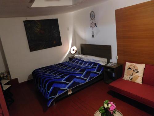 a bedroom with a bed and a red couch at MALA HIERBA in Cusco