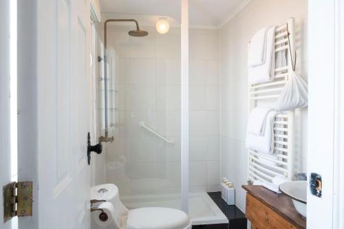a white bathroom with a shower and a toilet at Hotel Boutique La Yegua Loca in Punta Arenas