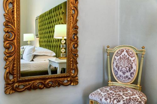 a room with a mirror, a chair, and a lamp at B&B Palazzo Cerami in Catania