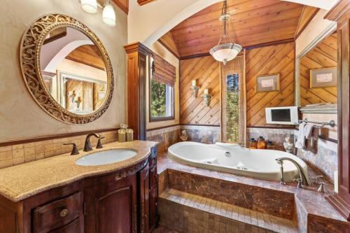 ein Badezimmer mit einer Badewanne, einem Waschbecken und einem Spiegel in der Unterkunft Beautiful 5bd Home with Pool Near LakePoint Sports in Cartersville