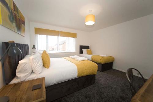 a hotel room with two beds and a window at Belmont Budget Apartment in Stockton-on-Tees