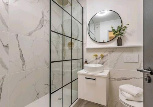 Un baño blanco con lavabo y espejo. en St Marg’s Hideaway; Grade II listed luxury apartment in the heart of Cheltenham - gateway to the Cotswolds! Sleeps 4 - outdoor seating and free private parking!, en Cheltenham