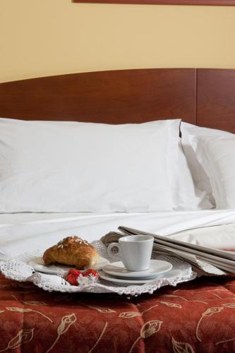a breakfast tray with a coffee cup and pastry on a bed at Hotel La Cascata in Azzano San Paolo