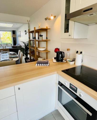 a kitchen with a counter top and a living room at Charmante petite maison flamande in Bondues