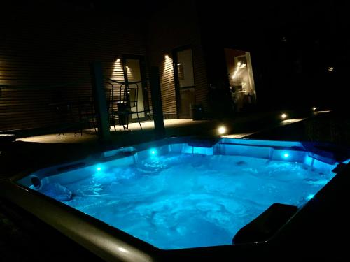 a hot tub with blue lights in a backyard at night at Wzgórze dobrostanu in Wilkasy