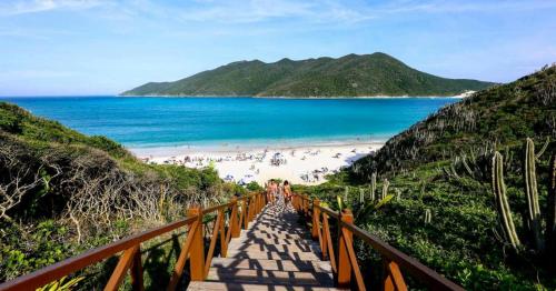 a boardwalk leading to a beach with people on it at Chalé Recanto dos Anjos Arraial do Cabo in Arraial do Cabo