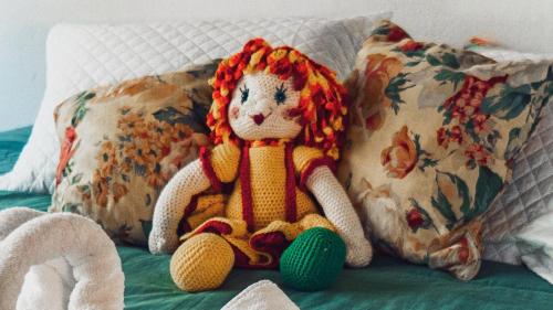 a crochet doll sitting on a bed with pillows at Chalés Tia Nastácia in Monteiro Lobato
