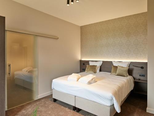 a bedroom with a large bed with white sheets and pillows at Boutique Hotel Ter Wallen in Izegem