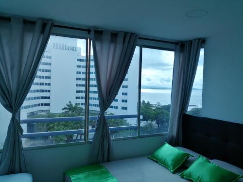 ein Schlafzimmer mit einem Bett und zwei großen Fenstern in der Unterkunft Sotavento Suites in Cartagena de Indias