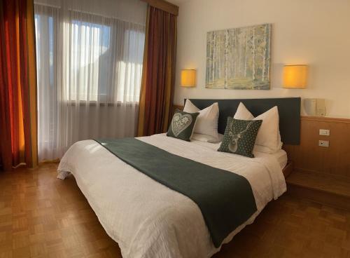 a bedroom with a large bed with two pillows at Hotel Arcobaleno in Fai della Paganella
