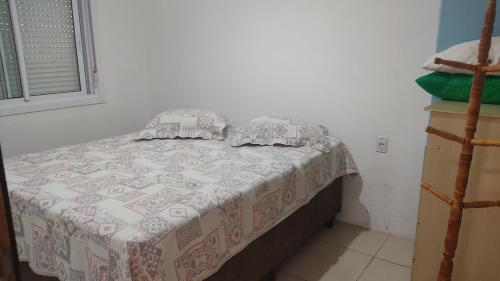 a bedroom with a bed with a quilt on it at Residencial Ramos in Torres