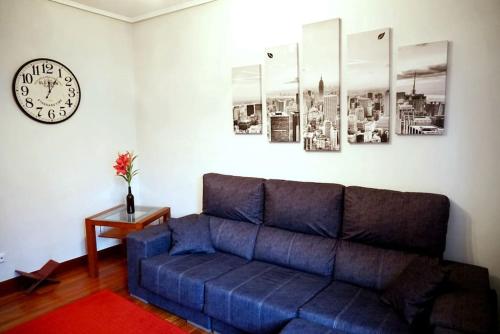 a blue couch in a living room with a clock at Apartamento centro Barakaldo BEC, Parking Incluido in Barakaldo