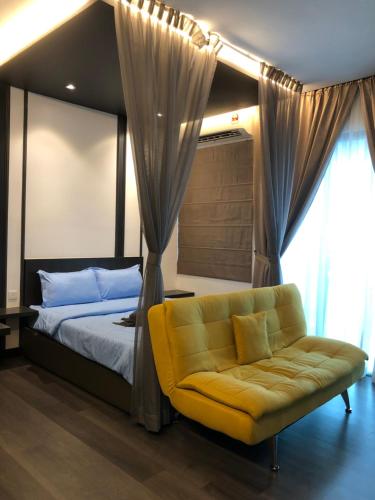 1 dormitorio con cama y sofá amarillo en Mishal’s Homestay-Vista Bangi Studio Service Apartment, en Kajang