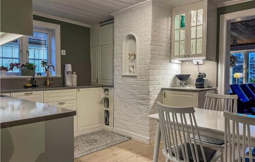a kitchen with white cabinets and a brick wall at Nice Home In Norrtlje With Wifi in Norrtälje