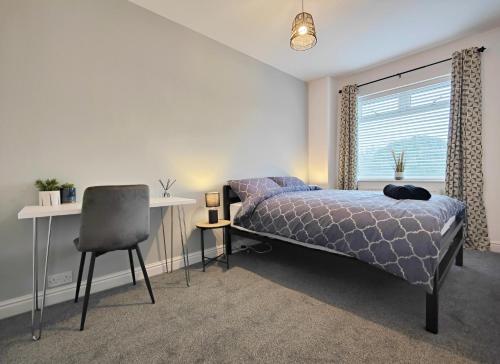 Stott House - Bright Spacious Townhouse 15 Minutes to Central Manchester With Free Parking في مانشستر: غرفة نوم بسرير ومكتب وكرسي