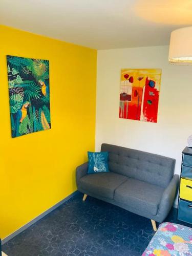 a living room with a couch and a yellow wall at Logement indépendant,calme à 2 pas du centre ville in Lannion