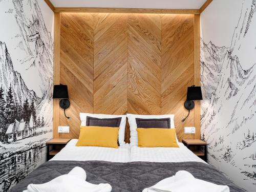 a bedroom with a large bed with two yellow pillows at Willa Roztoka & SPA - idealne miejsce dla Twojej rodziny in Bukowina Tatrzańska
