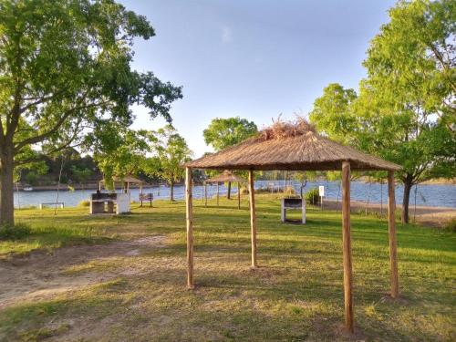 a straw hut on the grass near a body of water at Cabaña en el lago in Trapiche