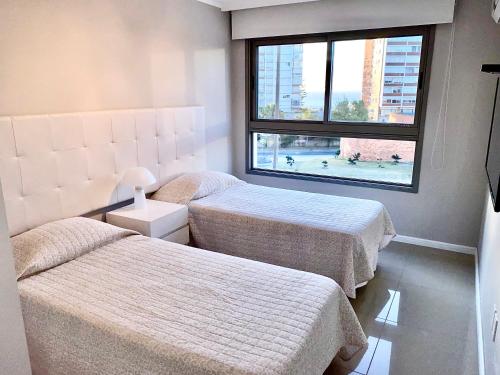 2 camas en una habitación con ventana en IMPERIALE Luxury Apartment, en Punta del Este