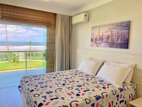 1 dormitorio con cama y ventana grande en Kalug - Duplex PÉ NA AREIA com 4 suítes, piscina e churrasqueira privativa na Praia do Sul! Perfeito para família - Wifi 300mb! en Ilhéus