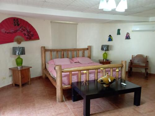 Schlafzimmer mit einem Bett mit rosa Bettwäsche und einem Tisch in der Unterkunft Sunrise Hostel Farallon in Río Hato