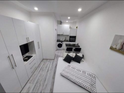 a white living room with a couch and a kitchen at Apartman Fortuna in Banja Luka