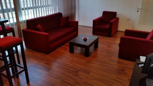 a living room with red chairs and a coffee table at Bed & Breakfast Twenty in Kikinda