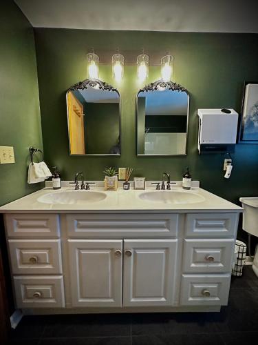 a bathroom with two sinks and two mirrors at HGTV Log Cabin near Lake Willoughby, Burke, Jaypeak ang Kingdom Trails in Barton