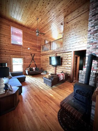 a large living room with wooden walls and a television at HGTV Log Cabin near Lake Willoughby, Burke, Jaypeak ang Kingdom Trails in Barton