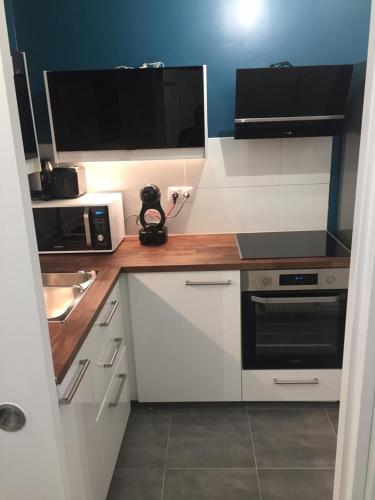 a small kitchen with white cabinets and a microwave at Bel appartement à 2 min des transports parisiens in Noisy-le-Grand