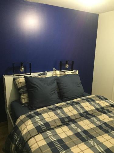 a bedroom with a bed with a blue wall at Bel appartement à 2 min des transports parisiens in Noisy-le-Grand