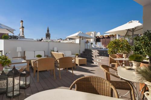a patio area with tables, chairs and umbrellas at Hotel Amadeus Sevilla in Seville