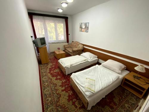 a hotel room with two beds and a chair at Penzión Jazmín in Prašice