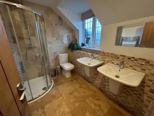 a bathroom with two sinks and a shower and a toilet at Castlebar in Great Singleton