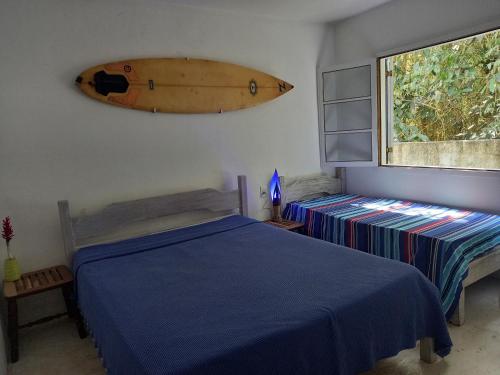 a bedroom with a bed and a surfboard hanging on the wall at Casa sossegada ao lado da natureza e do mar in São Sebastião