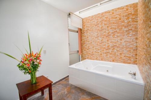 a bathroom with a white tub and a brick wall at Hotel Monarca Armenia in Armenia
